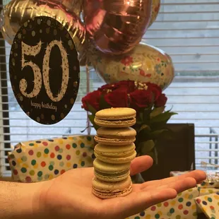 a hand holding a stack of macarons