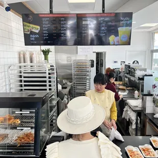 a woman in a white hat standing in front of a counter