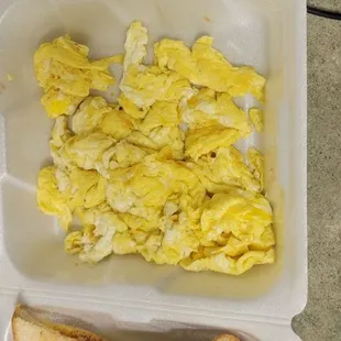 scrambled eggs and toast in a styrofoam container