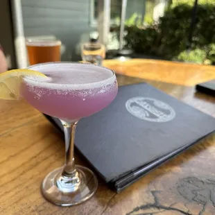 a pink cocktail with a lemon garnish