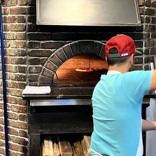 a man putting a pizza into a brick oven