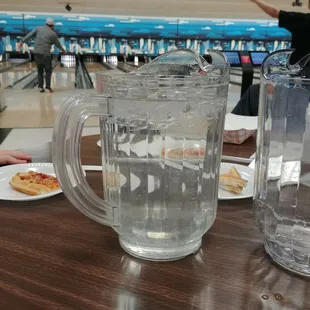 a pitcher of water and a plate of pizza