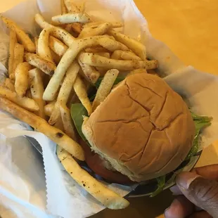 a hand holding a basket of french fries