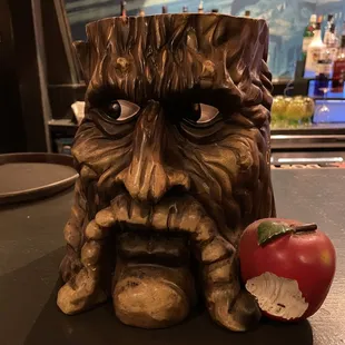a tree stump with a face and an apple