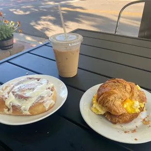 Cinnamon Roll, iced latte, breakfast croissant sandwich