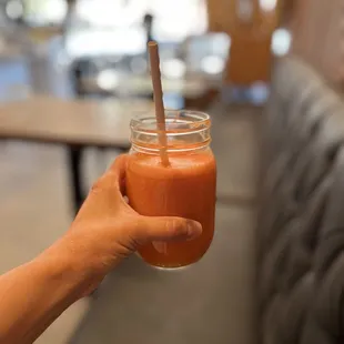 a hand holding a jar of smoothie