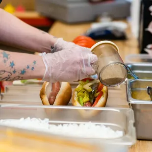 a person putting mustard on a hot dog
