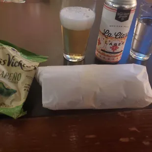 a beer, chips, and a snack on a table