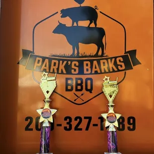 two trophies in front of a sign