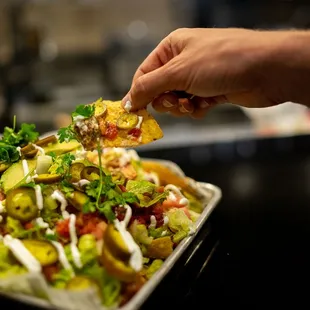 a person taking a piece of nachos
