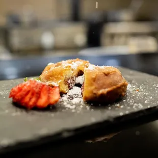a plate of pastries with powdered sugar and strawberries