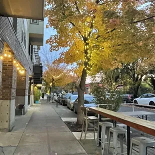 a view of a sidewalk with tables and chairs