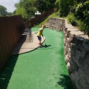 a young boy playing miniature golf