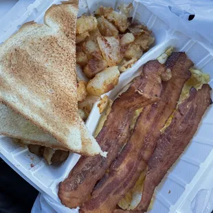 bacon, eggs, and toast in a styrofoam container