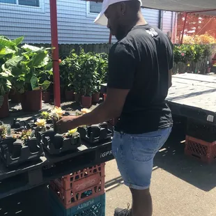 a man standing in front of a table of plants