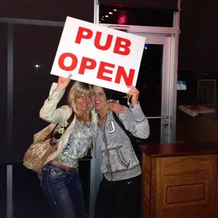two women holding a pub open sign