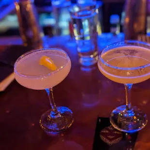 two cocktail glasses on a bar