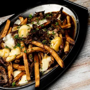 a platter of fries with shredded beef and cheese