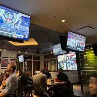 people sitting at tables watching tvs