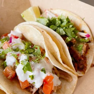 two tacos with toppings in a box