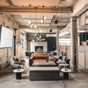 a large open space with couches, tables, and a projector screen