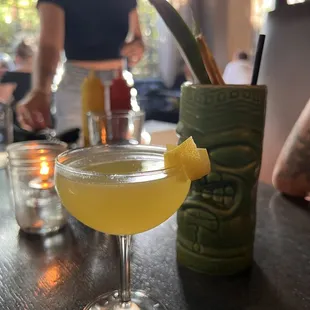 The tiki cup has a rum drink, the other one is a citrus spritzer.