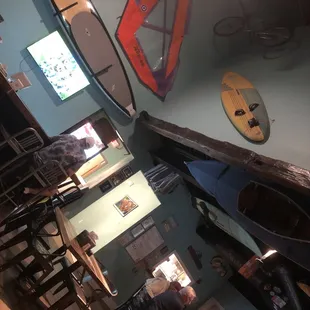 The high ceiling and wall area with sell boards and paddleboard&apos;s and such