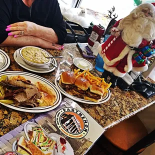 a santa clause sitting at a table with plates of food