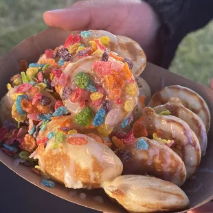 a person holding a bowl of cereal donuts