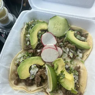 4 steak tacos with onion, cilantro, and avocado.