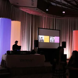 Screen and projector system with fabric LED glow columns on stage.