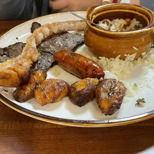 Steak, pork fritter, chorizo , amarillos (sweet plantains) white rice, red beans and an egg.