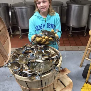 a girl holding a bucket of crabs