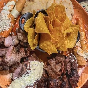 Plato catracho, pork, carne asada, taquitos, pupusas, stuffed plantain and anafre with chips, beans and cheese.