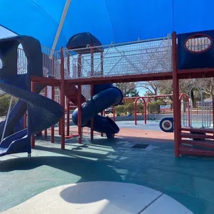 Part of the large playground with cover from the sun, swings in the background.