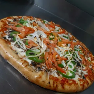 a pizza with tomatoes, onions, peppers, and cheese