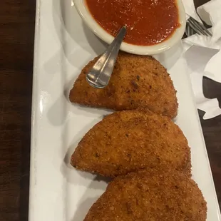 three pieces of breaded pastries and a bowl of sauce