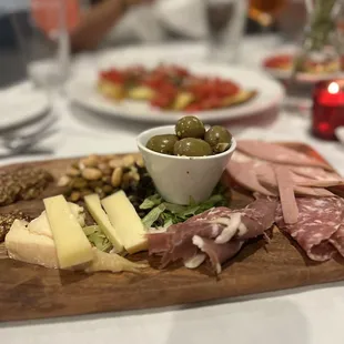 a platter of meat, cheese, olives, and bread
