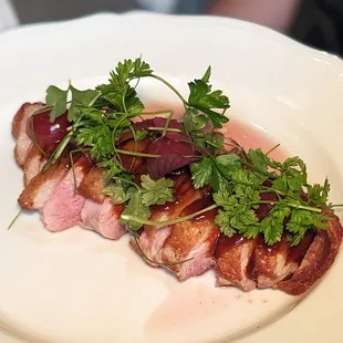 a plate of food with meat and garnish