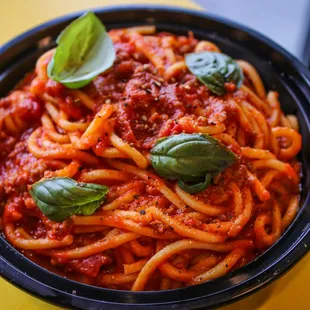 a bowl of spaghetti with sauce and basil leaves