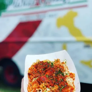 a hand holding a container of pasta galifi