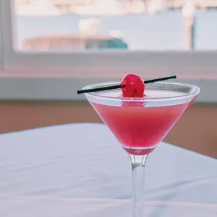 a pink cocktail with a cherry garnish