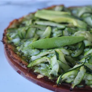Our NEW Green Goddess Pizza is made with. a cauliflower crust, vegan pesto, roasted zucchini, topped with avocado &amp; basil.