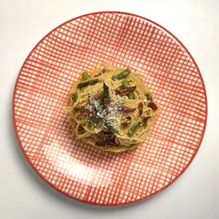 a red plate with a pasta dish on it
