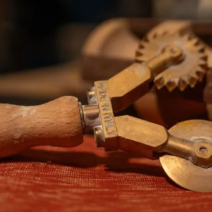 a pair of pasta cutters and a wooden rolling wheel