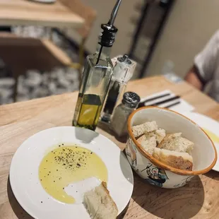 a bowl of olive oil and bread on a table