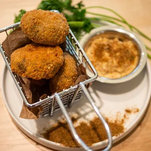 a basket of fried food and a bowl of dip