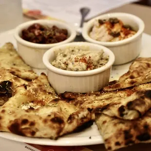 a plate of food with pita chips and dips