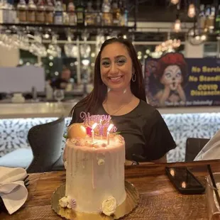 a woman sitting in front of a cake