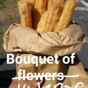 a hand holding a bag of churros